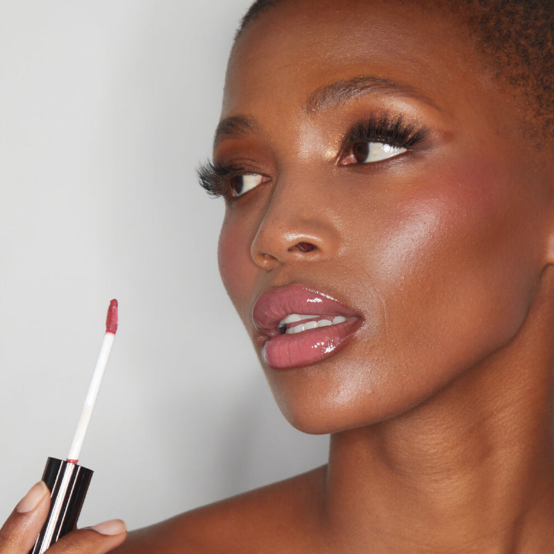 Model showcasing the radiant effect of the SOSU x Bonnie Ryan rosy pink lip gloss, highlighting its lustrous finish on her lips, complemented by a soft shimmering eye makeup.