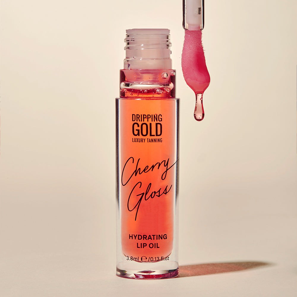 A bottle of Cherry Gloss Hydrating Lip Oil from Dripping Gold Luxury Tanning, perfect for achieving ultra-soft and glowy lips with just one swipe