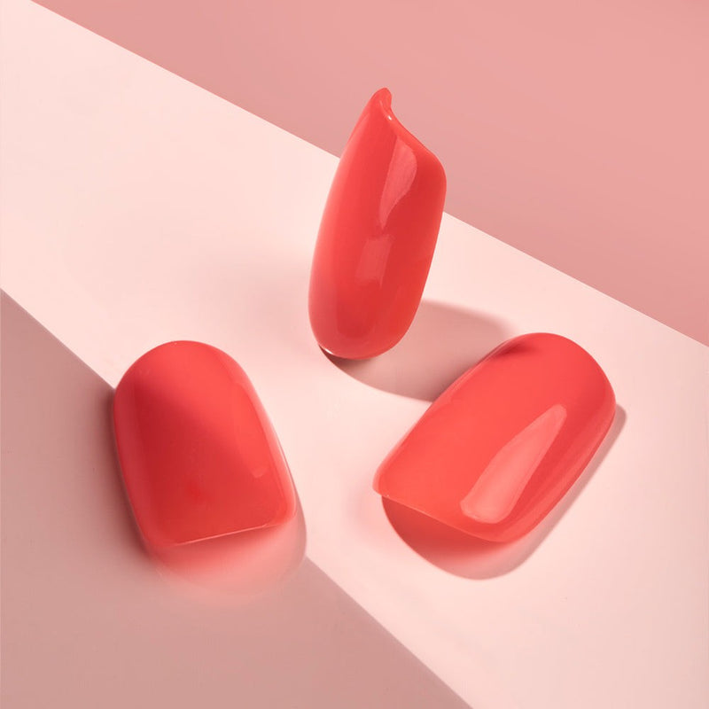 Square-shaped short-length Coral Kiss Faux Nails in a trendy, bold coral color with an extreme gloss finish