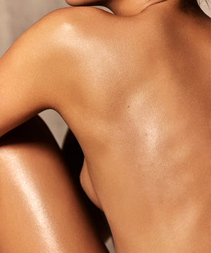 Woman's back and side profile showcasing glowing golden skin, representing the 'Body Finish' collection.