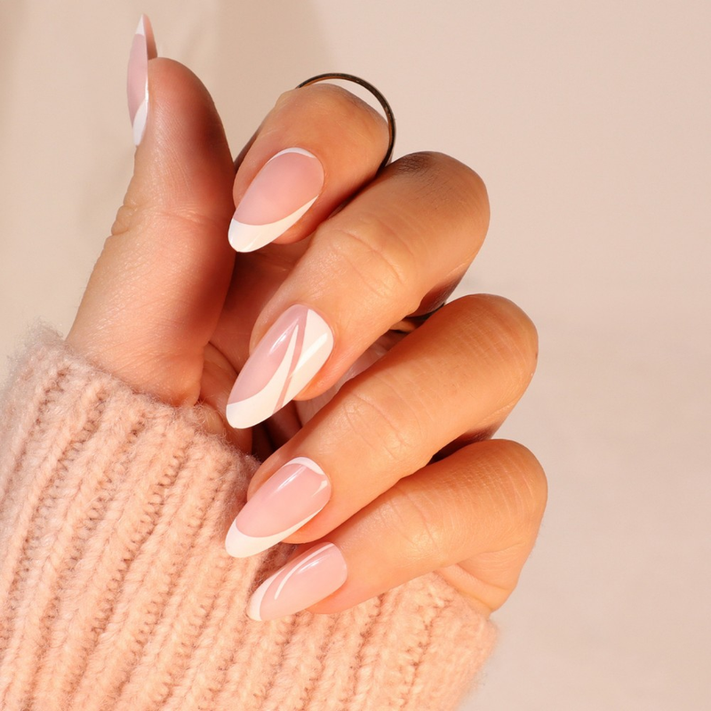 A classic French manicure with a twist featuring soft nude nails with stylish white nail art in a long stiletto shape