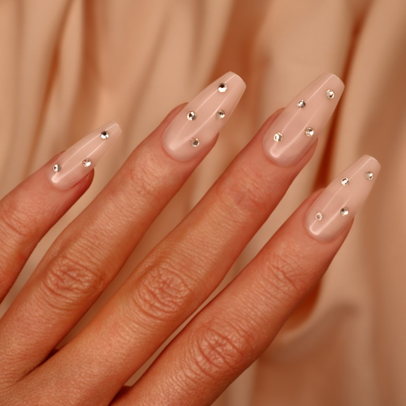 An elegant set of Shine Bright nails in a classic nude color with trendy jewel accents, designed for easy application and an extreme gloss finish
