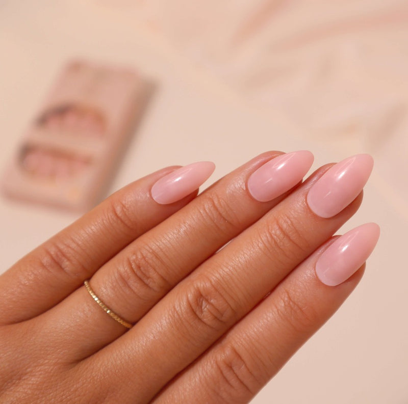 A hand wearing Soft & Subtle sleek stiletto shaped medium length nude nails with a subtle pink undertone, giving salon results in seconds